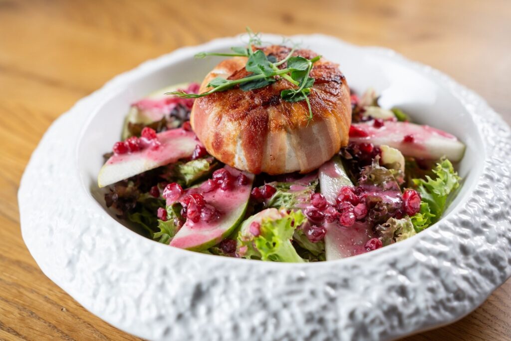 Grilovaný hermelín posazený na listovém salátu, doplněný hruškami a brusinkovým dresinkem.