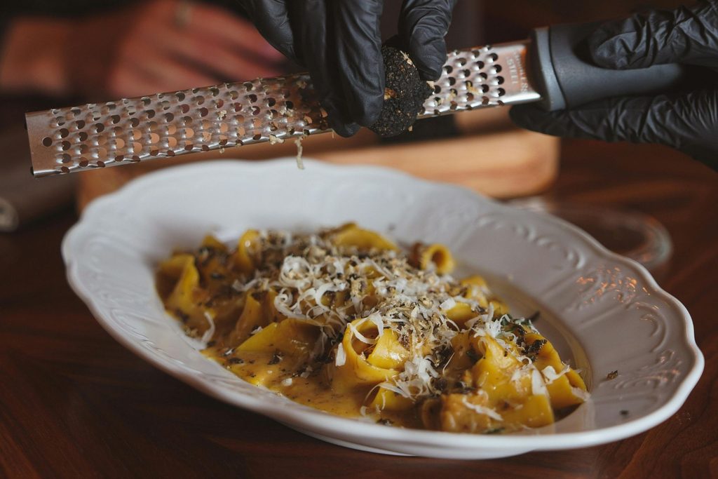 Čerstvý černý lanýž strouhaný na těstoviny s krémovou omáčkou a parmazánem – využití lanýžů v italské gastronomii.